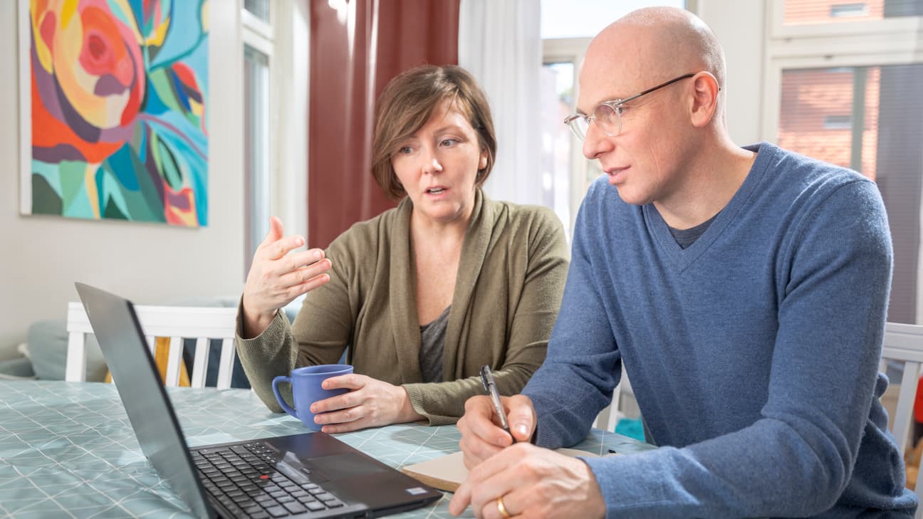 Kvinna och man som sitter vid en laptop